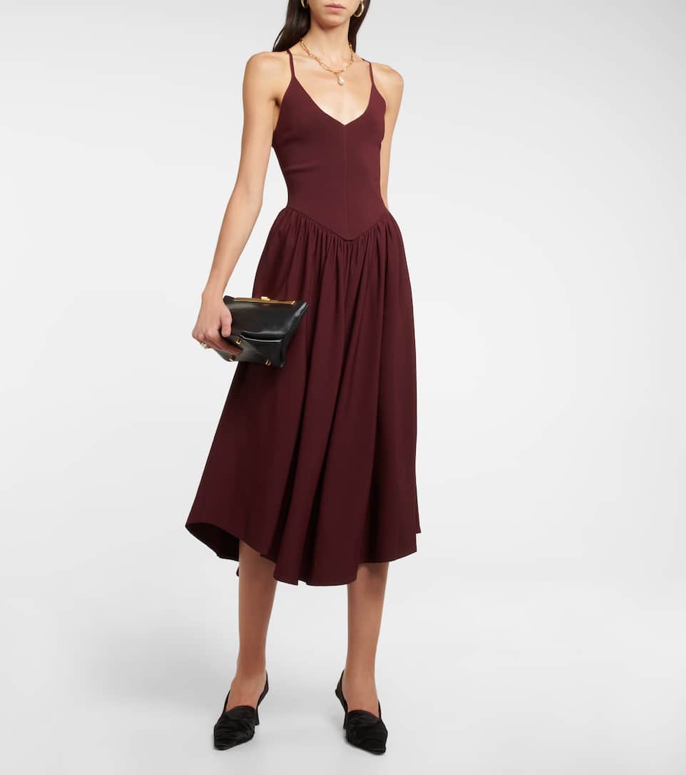 Khaite’s Mila midi dress is shaped with a Basque waistline, full-bodied skirt, and asymmetrical hem. The halter crossover ties and V-shaped scoop neckline that mirrors the V-shaped waist panel flatter any and every figure