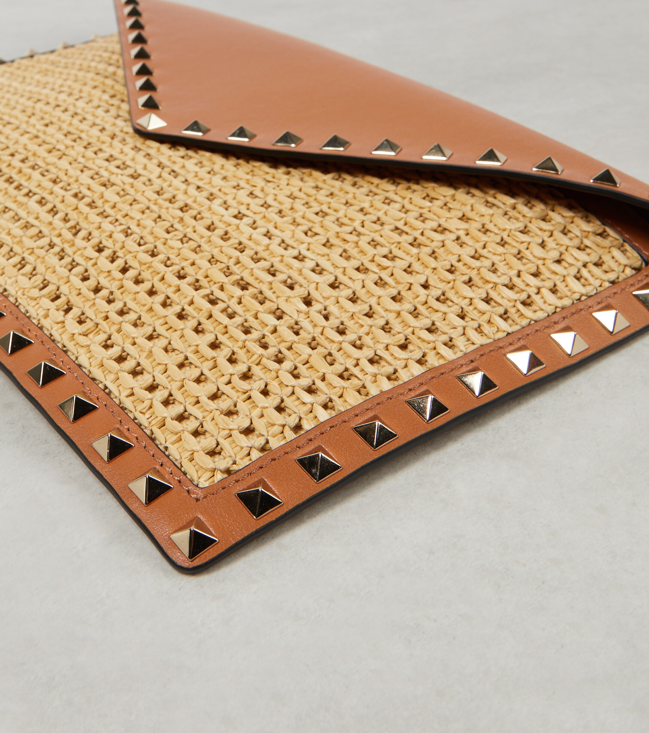 Valentino Garavani Rockstud Large leather-trimmed raffia clutch thumbnail
